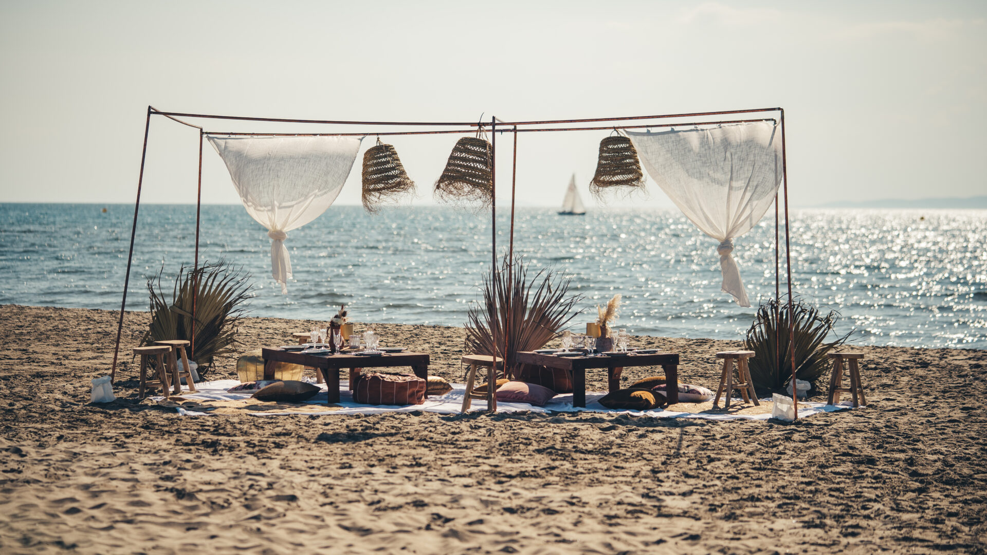Banc de sable Bohème mobilier avec vue sur un catamaran au loin avec bokeh, Catamaran Lucile sorties en mer à la Grande Motte